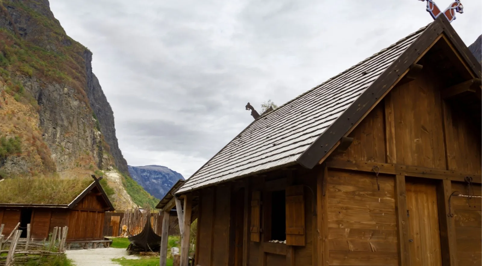 Turf-roofed Viking-style longhouses at the foot of a steep fjord valley