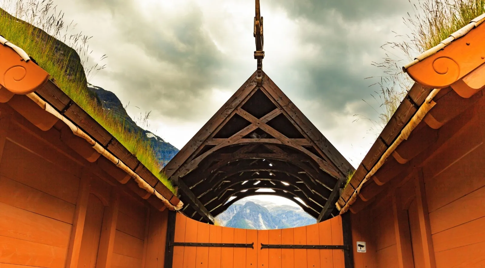 Looking up at the timber gable and turf roofline of a Viking-style longhouse gateway
