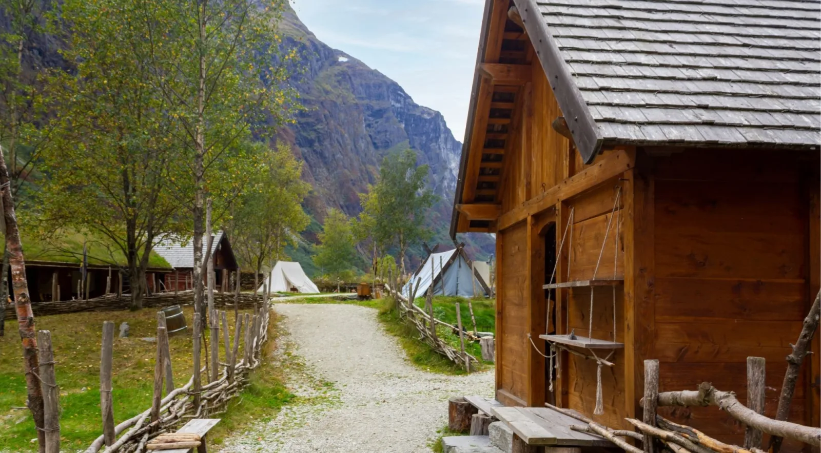 A gravel path through the village past canvas tents and timber buildings, framed by steep mountainsides